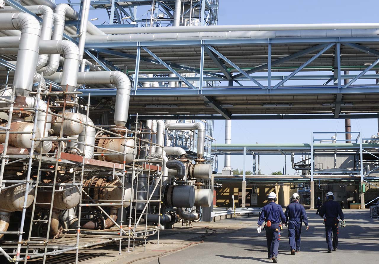 Intricate oil and gas refinery with a network of pipes and contractors monitoring on-site